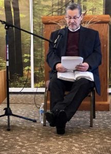 Michael sits on a chair in front of the church podium to give his last sermon.