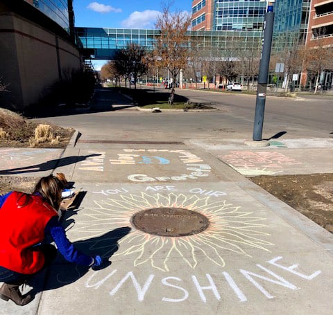 UCHealth volunteers chalk the walk outside of UCH.