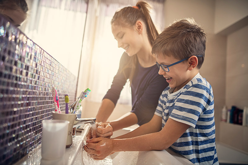 kids laughing while washing their hands, important in preventing the spread of coronavirus.