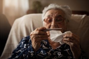 symptoms, like this older women holding a thermometer, is answered in this COVID-19 FAQ.