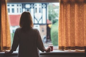woman looking out window demonstrating we have fears and fight-or-flight responses to the coronavirus right now.