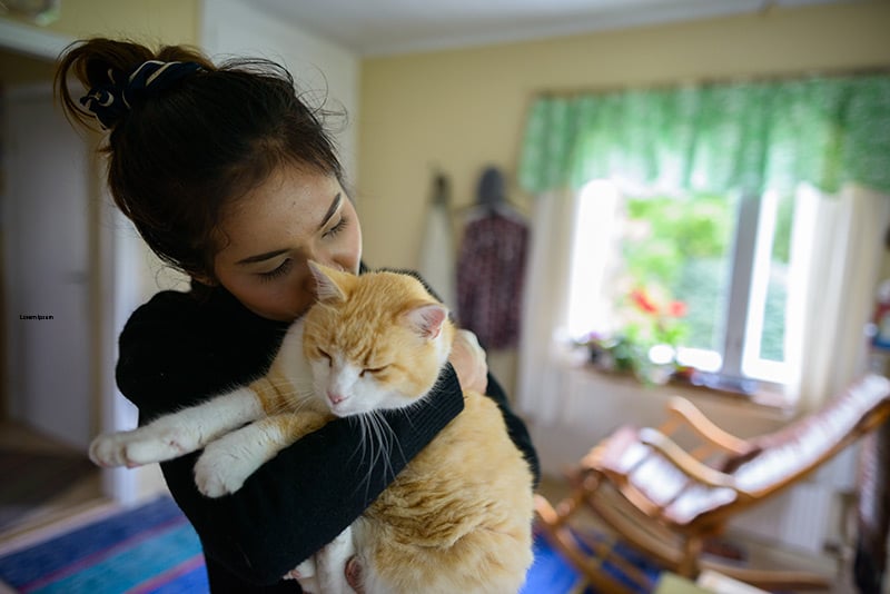 Woman hugs her cat, which as long as you are not sick with COVID-19 is ok for pet owners to do.