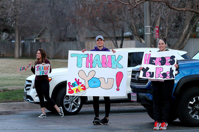 three young women hold signs, showing their thanks to health care workers in Colorado during Covid-19 outbreak