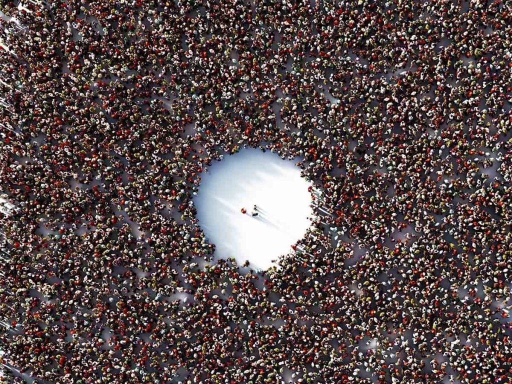 a large crowd with an opening of just a few in the middle, signifying herd immunity.