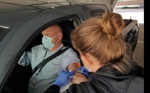 A nurse draws blood from a man who is seated in his car as part of a new drive-thru lab service in Colorado at UCHealth.