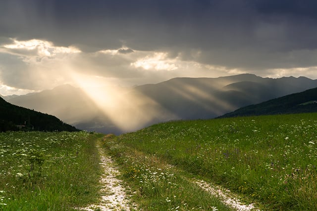 A stormy scene in the mountains with a ray of light signifying the impact of COVID-19 and suicides in Colorado.