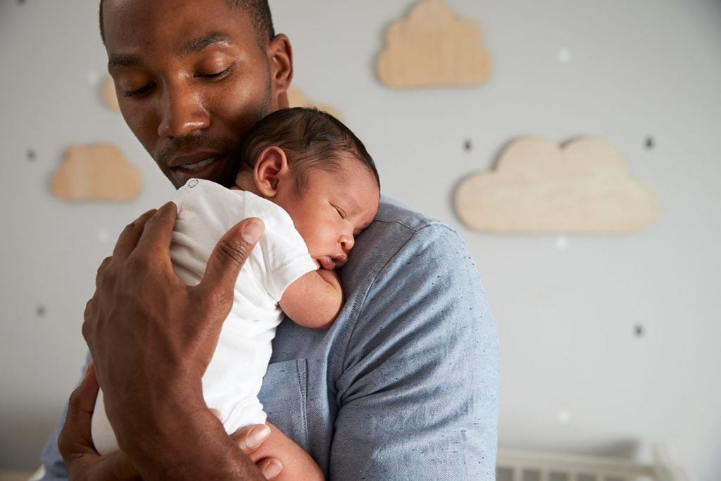 A father holding his newborn child in a nursery, knowing what to expect as a new dad.