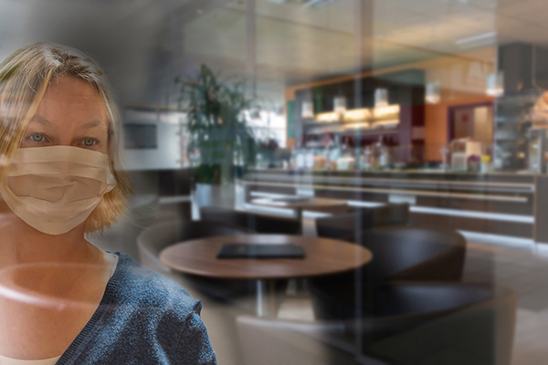 Concerns about airborne COVID-19 are increasing. Here, a woman wearing a masks gazes inside an empty restaurant.