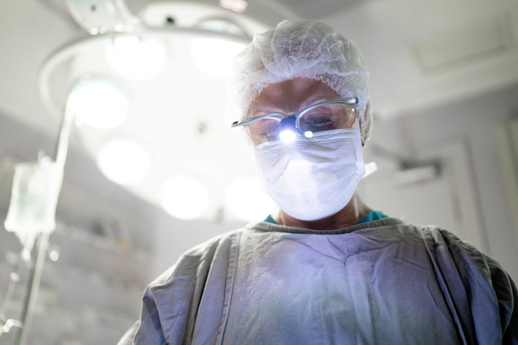 A doctor performs plastic surgery in an operating room.