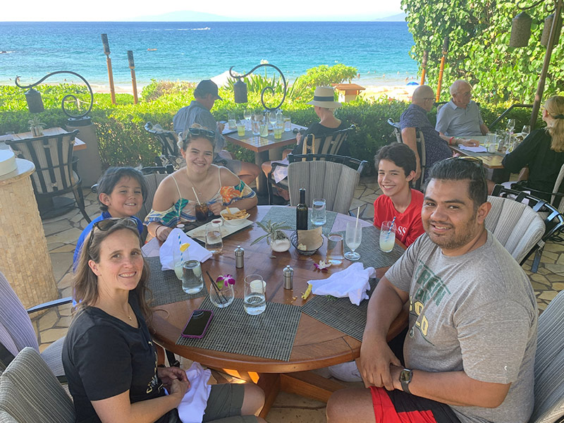 family sits around a table in Hawaii