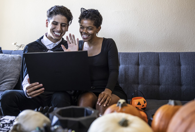 couple dressed in costume does halloween safely during covid by participating in an online party.
