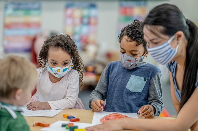 Asymptomatic COVID-19 infections are common in people of all ages, including children. Here, children wear masks while they color at school.