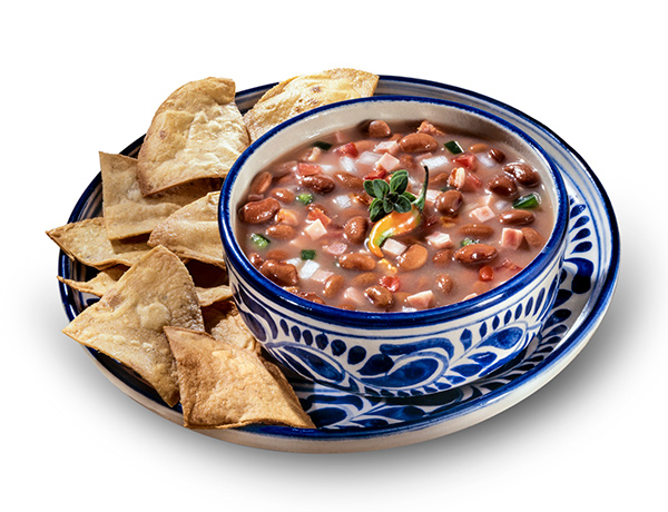 Frijoles charros on a plate with chips.