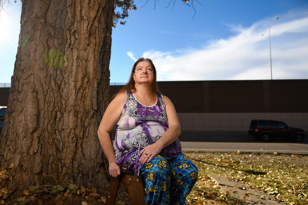 Norma Armistead is seated under a tree