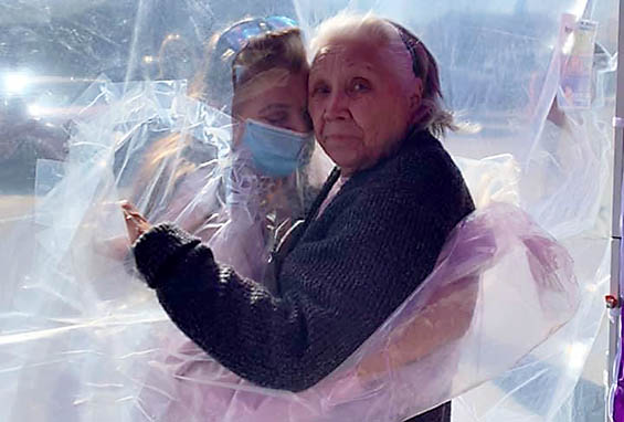 Tina and Dorothy embrace through a 'hug tunnel' created help with elderly isolation created by the pandemic.