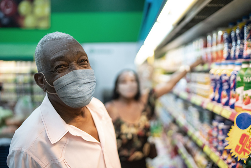 Older man in a grocery store wearing his mask. Wear a mask even after COVID-19 vaccine.