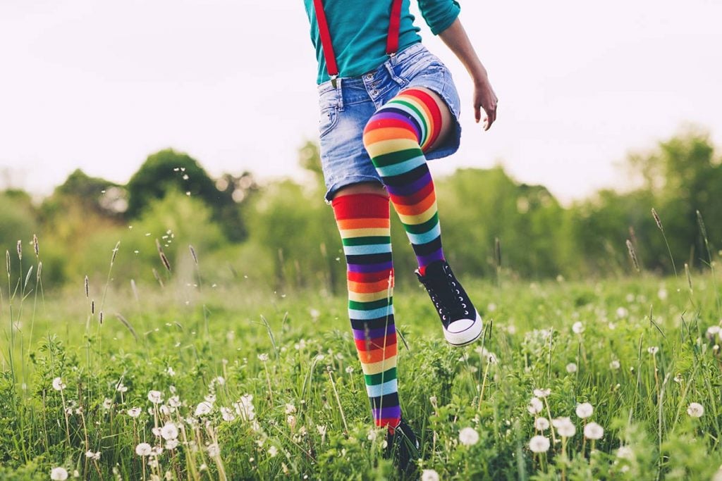 A woman in colorful socks steps through a field of flowers