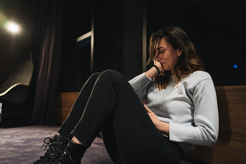 woman with suicidal ideation crying in a dark room.