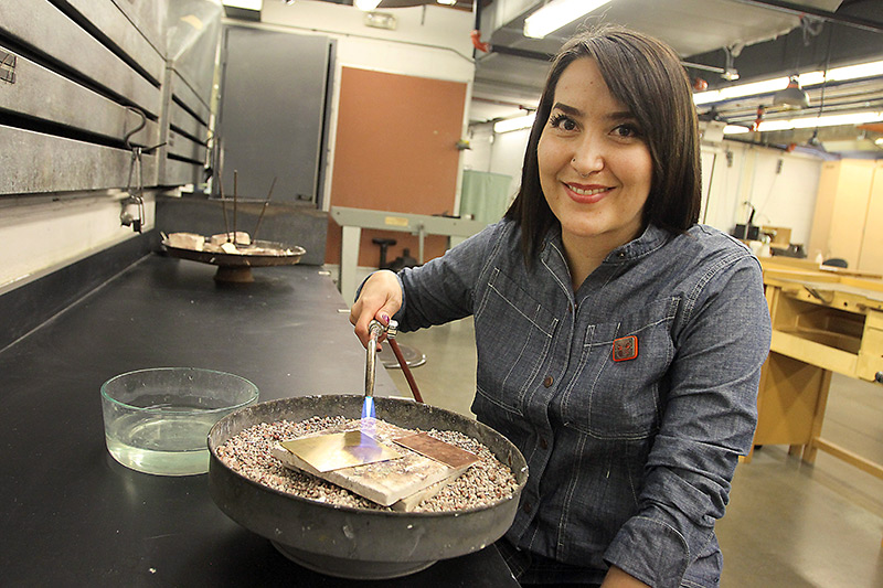Priscilla Gonzalez doing metalsmithing. Her art demonstrates her efforts for colon cancer awareness.