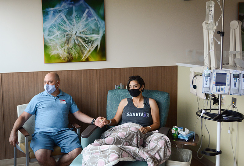 Cathy and Tony Pane hold hands as she receives her final infusion treatment at UCHealth Highlands Ranch Hospital.