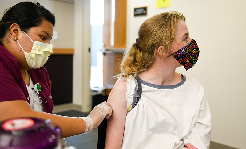 Kate Williams turns away as she receives a vaccine at UCHealth University of Colorado Hospital.