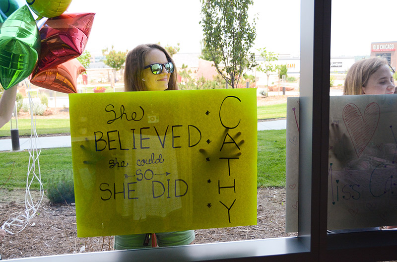A friend holds a poster outside UCHealth Highlands Ranch Hospital as Cathy Pane finishes her final infusion treatment.