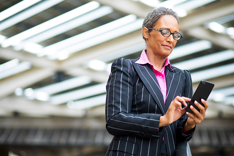 business woman looks to her phone to verify vaccination records while traveling.