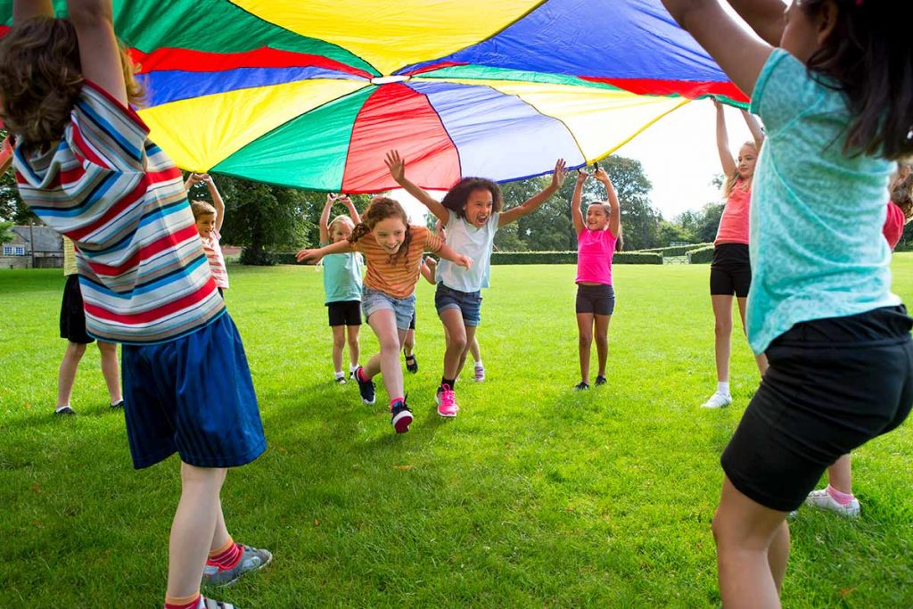 Kids playing under a canopy in a park with green grass as part of safe party planning ideas.