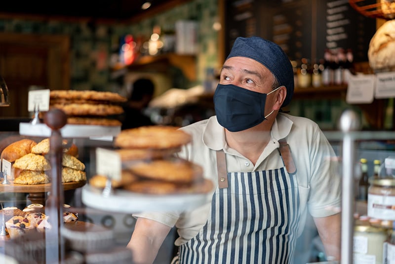 The delta variant and vaccines. A man working at a cafe wears a mask.