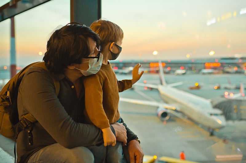 The delta variant and masks. A father and son wear masks at an airport.