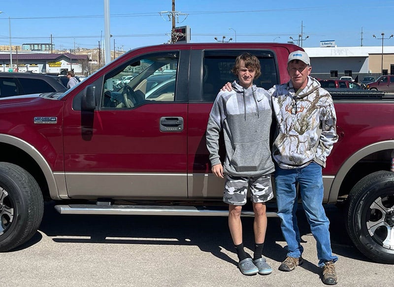 Craig, who manages his Parkinson's disease with deep-brain stimulation, stands beside his grandson in front of a truck.