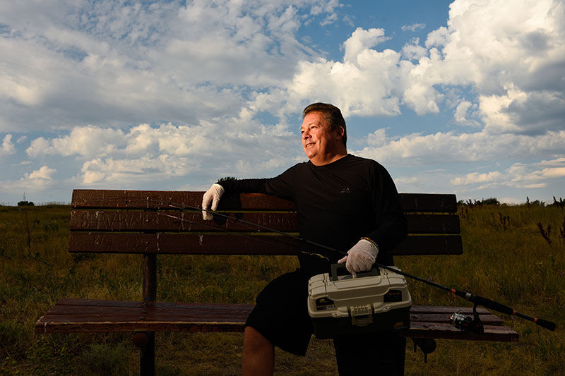 56-year-old man sitting on a bench with his fishing tackle will be one of those who get a third dose of COVID-19 vaccine because he had a liver transplant..