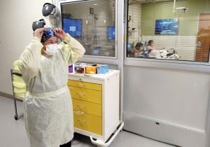 A nurse dons Personal Protective Equipment before entering a patient room at Poudre Valley Hospital.