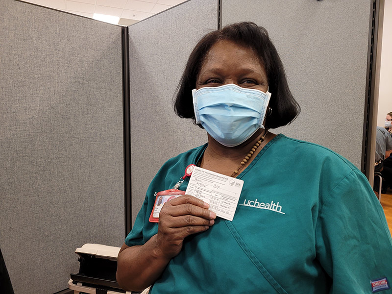 Paige Davis, an environmental services professional at UCHealth Memorial Hospital shows her vaccine card.