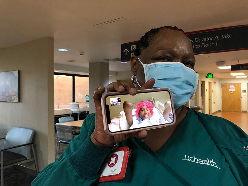 Paige Davis holds up a cell phone that shows her daughter, Candice, in a hospital bed in Philadelphia with her arms amputated because of COVID-19.