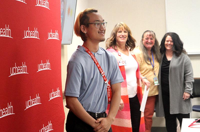 Project SEARCH intern Tha Blay Htoo poses for a photograph while his supporters cheer him on during a special “signing” event for the five new Project SEARCH interns that will start at UCHealth Greeley Hospital in the fall 2022. Photo by Kati Blocker, UCHealth.