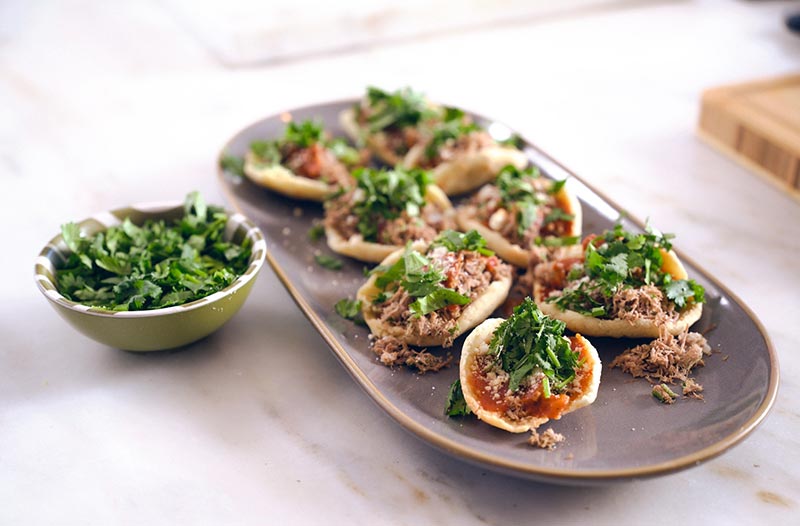 Garnachas are a traditional Guatemalan dish made with small, thick masa tortillas filled with marinated meat and tomatoes and topped with cabbage, salsa and queso fresco..