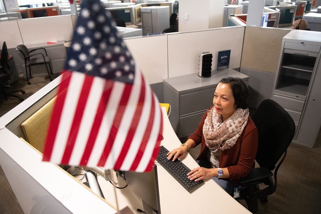 Anna Salvador at a cubicle at the Colorado Springs USAA office where she works in the banking division, during and after battling triple-positive breast cancer.