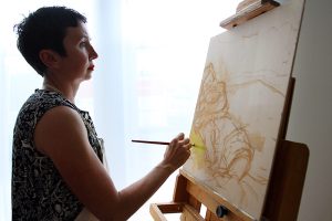 Taryn Sargent paints a canvas that is positioned on an easel.