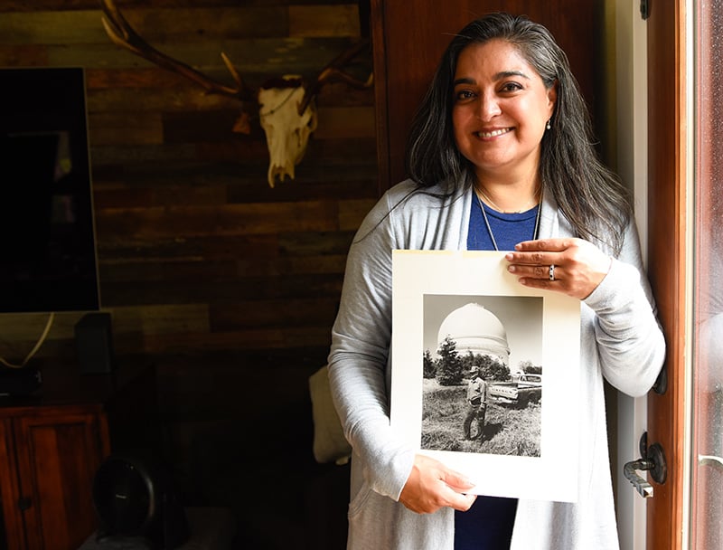 Dr. Abbey Lara holding a photo of her dad with the telescope that he helped maintain in California. Photo by Cyrus McCrimmon for UCHealth.