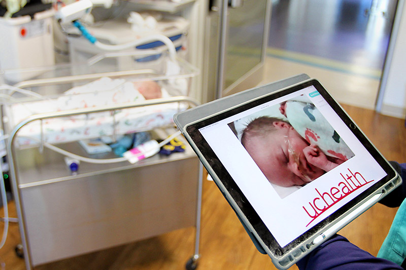 nurse holding up a tablet that demonstrates how a parent can veiw the NICU camera when they're not able to be in the room.