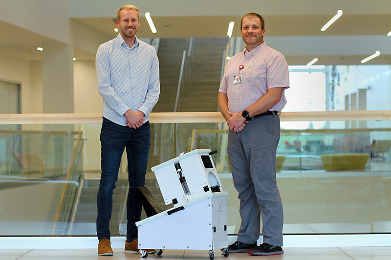 Kevin Labus,, left, a research scientist with CSU and co-investigator on a tibia fracture study, and Nikiah Nudell, manager of the trauma research team at Medical Center of the Rockies, stand in front of the device used in their tibia fracture study.