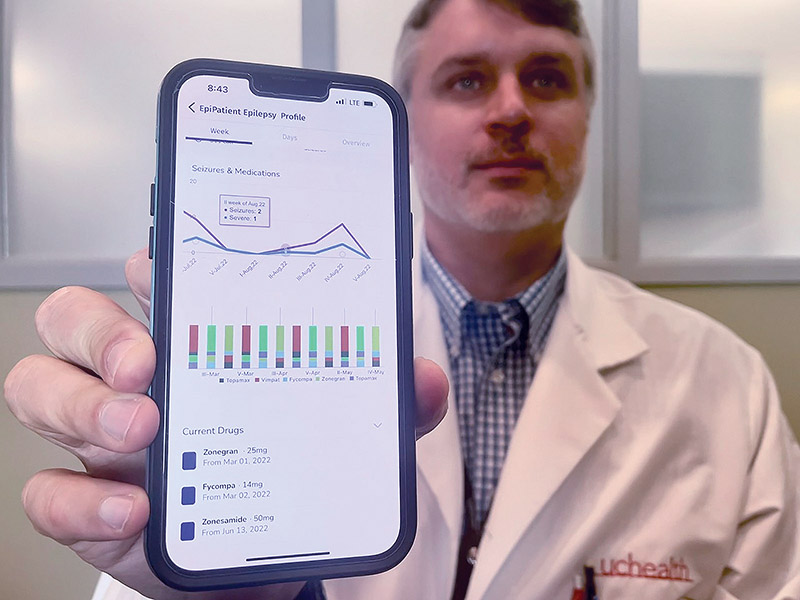 man holding his smartphone up to show how it works with the drug-resistant epilepsy study.